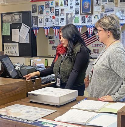 Assisting new postmaster Esmeralda Aguirre in transfer the Floydada post office into her name is Tammy Salinas (right), Petersburg postmaster. | HESPERIAN-BEACON