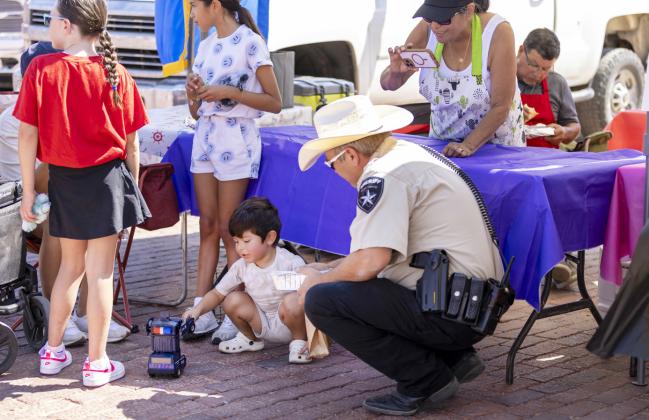LOCKNEY CITIZENS OF ALL AGES celebrated Lockney Old Fashioned Day last Saturday, Aug. 2025, with food and vendor booths, a dunking tank, and fun and games. Xander Rodriguez (center) ogf Lockney gave some tips to a Floyd County deputy on how to manage a vehicle pursuit! MORE PHOTOS, PAGE 5 | CERVANTES PHOTOGRAPHY