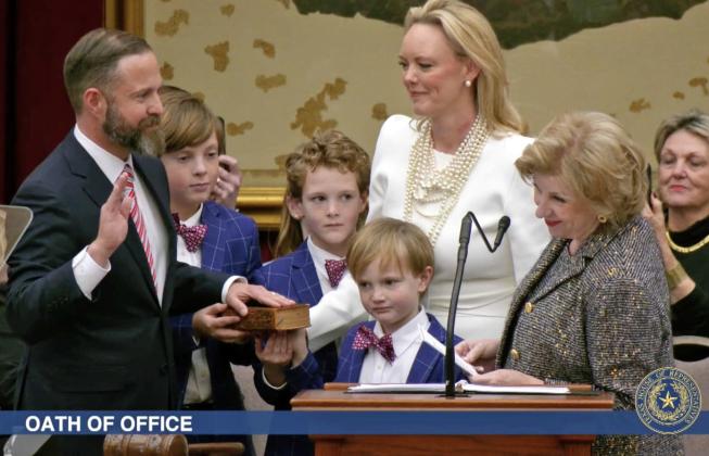 ELECTED TX SPEAKER State Rep. Dustin Burrows was administered the oath of office as Speaker of the Texas House by Secretary of State Jane Nelson (right) during opening day ceremonies on the House floor on Tuesday, Jan. 14, 2025, as Burrows’ wife, Elisabeth (in white dress), and children look on. | BOB DAEMMRICH FOR THE TEXAS TRIBUNE
