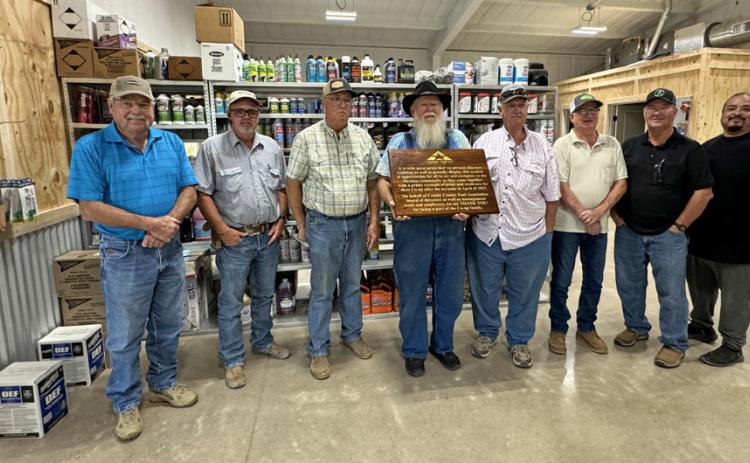 CROSBY COUNTY FUEL ASSOCIATION GRAND REOPENING PRIDE AND RESILIENCE are celebrated in the text of the large, custom-made wooden plaque presented to the Crosby County Fuel Association’s McAdoo location last Friday by general manager Steve Riley. From left, board members Bobby Binder, Dusty Cornelius, Joe Mark Cargile, Mack Gardner (with plaque), Mark Schoepf, Brad Aycock and Russ Edinburgh, and store manager Luis Guzman. | THE TEXAS SPUR